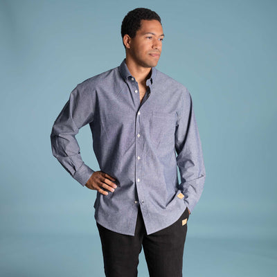 Man wearing a blue button-up 100% organic cotton shirt against a light blue background